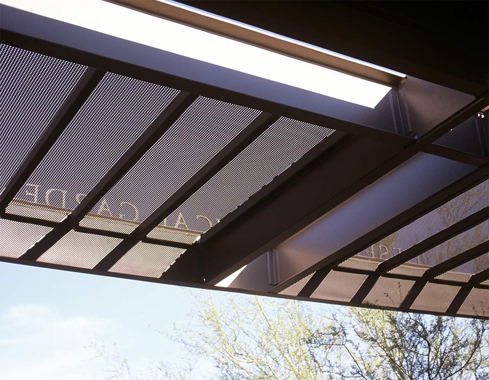 Transitional shade elements and signage at canopy edge.